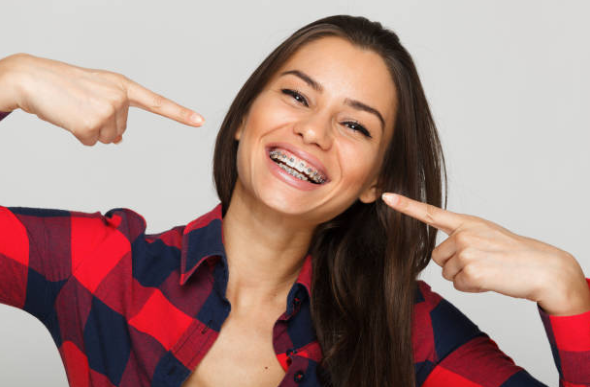 Patient smiling and pointing to braces